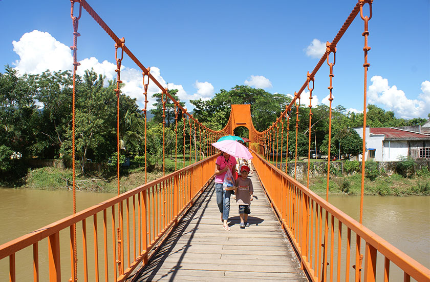 Orange bridge over Nam Song River leading to Tham Chang Cave in Vang Vieng