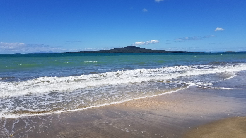 Emerald water and Rangitoto Island seen from Takapuna Beach in North Shore